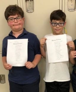 boys standing in front of the lockers holding up their paperwork