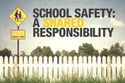 School Safety sign on vast land with picket sign and tall grass