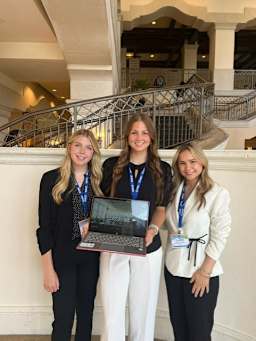 three TCHS TAFE students holding a laptop
