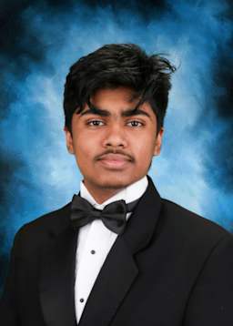 The image depicts a young man wearing a formal black tuxedo with a bow tie, standing against a blue smoky background.