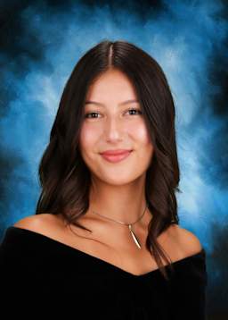 The image shows a young woman with long, dark hair and a warm, friendly smile against a vibrant blue background with a hint of smoke or mist.