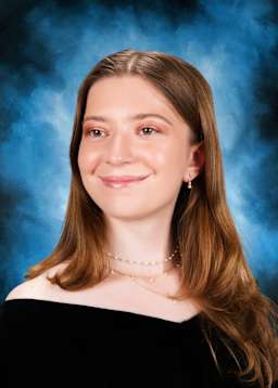 The image shows a young woman with long, brown hair and a warm, friendly smile against a blue background.