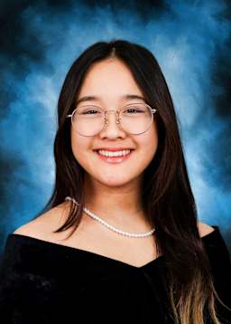 A smiling young woman with long dark hair and glasses, set against a blue background.