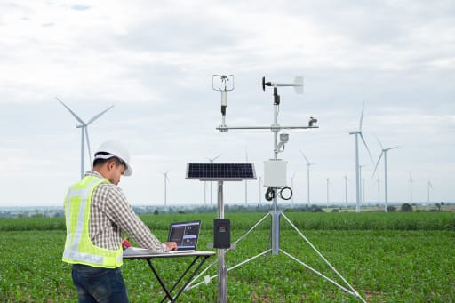 A geologist works on a mobile work station in a wind farm field.