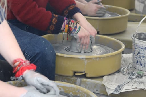 Student working clay on a pottery wheel in Art Class
