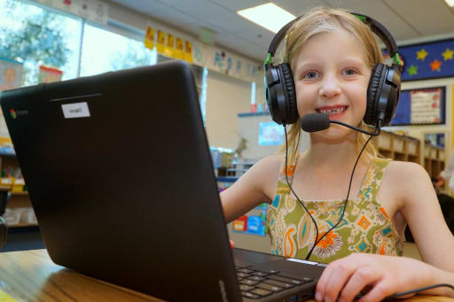 Girl student with headphones working on laptop