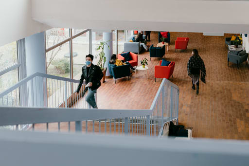 A student walks up a flight of stairs from a student lounge area