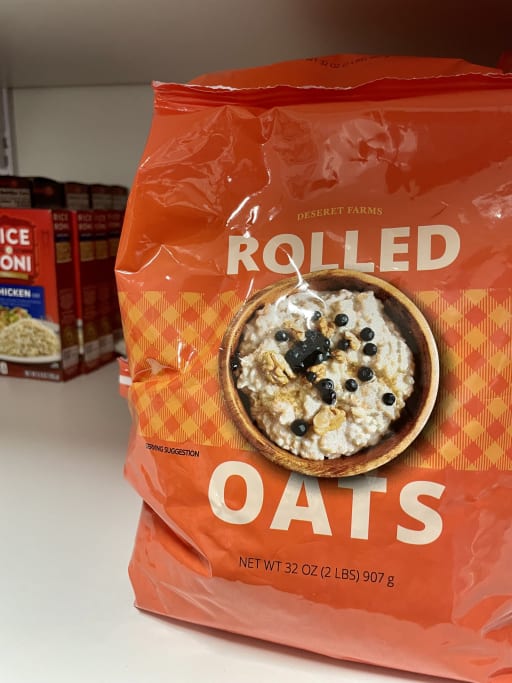 Red bag of rolled oats on a store shelf with visible text and an oatmeal image. Nearby are Rice a Roni boxes. The scene is bright, conveying a shopping context.