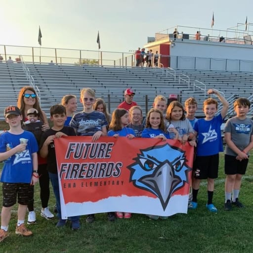 group of Adena Students outside on football field with banner that reads Future Firebirds