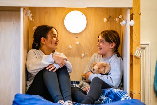 Two Felsted boarders in casual clothes in nook of bunk bed chatting.