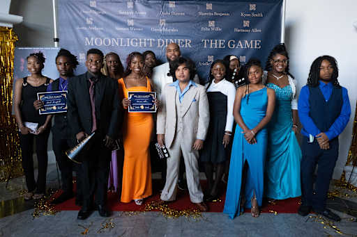 A group of students gathers around Mr. John P. Wheatley on the red carpet