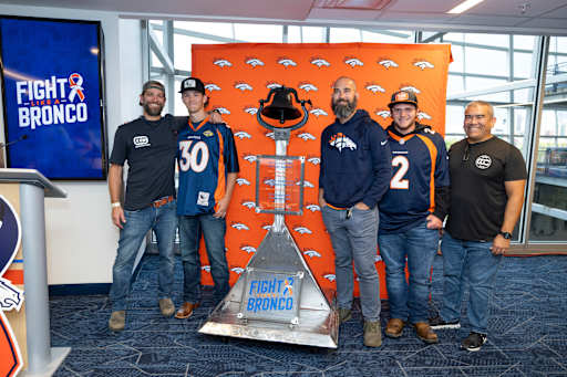 Teachers and two students stand next to the bell for photo.
