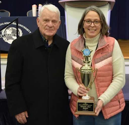 Two people standing with Model UN trophy