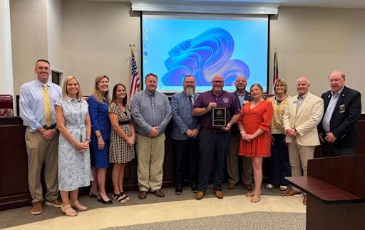 Dr. Swan shown in the center holding a plaque while flanked on both sides by several adult administrators.