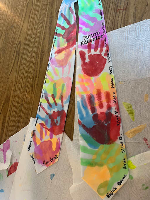 white graduation stole with multi-colored children's handprints in bright paint
