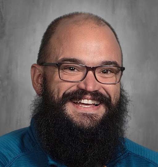 School photo of Jarod Mills. He is bald with a black beard, wears glasses and is smiling.