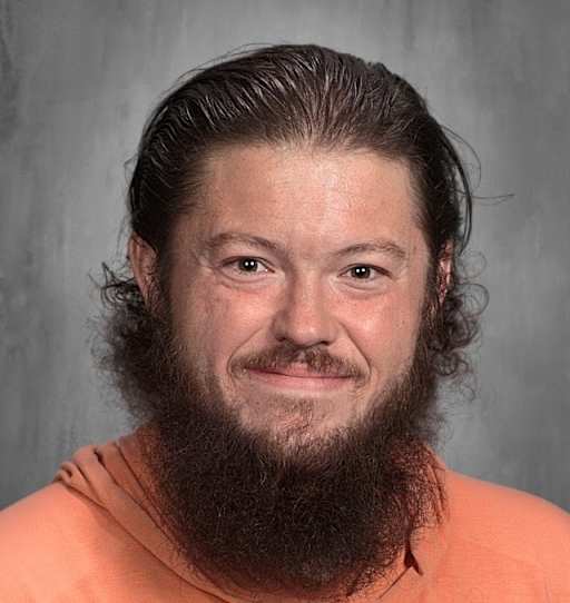 School photo of Johnathan Woodall. He has long dark hair and a dark beard. He is smiling