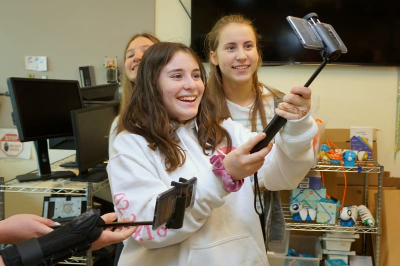 Middle school girls taking pictures with selfie stick