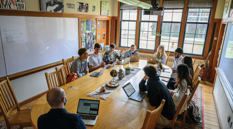 Students sit around a harkness table during an English class 