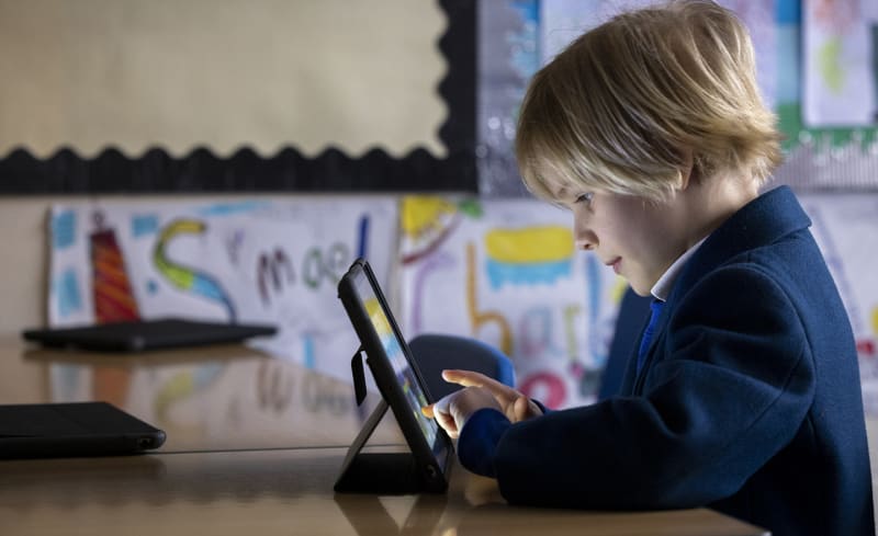 A Junior School child working on an iPad in a classroom.