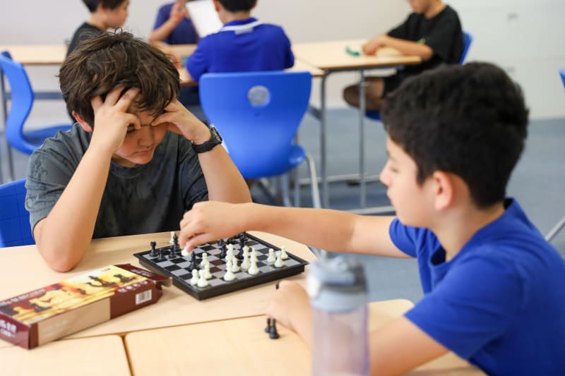 Two boys face off over a chess board