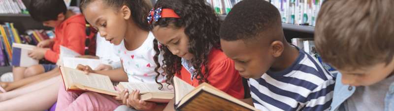 Students sitting on the floor in the library reading