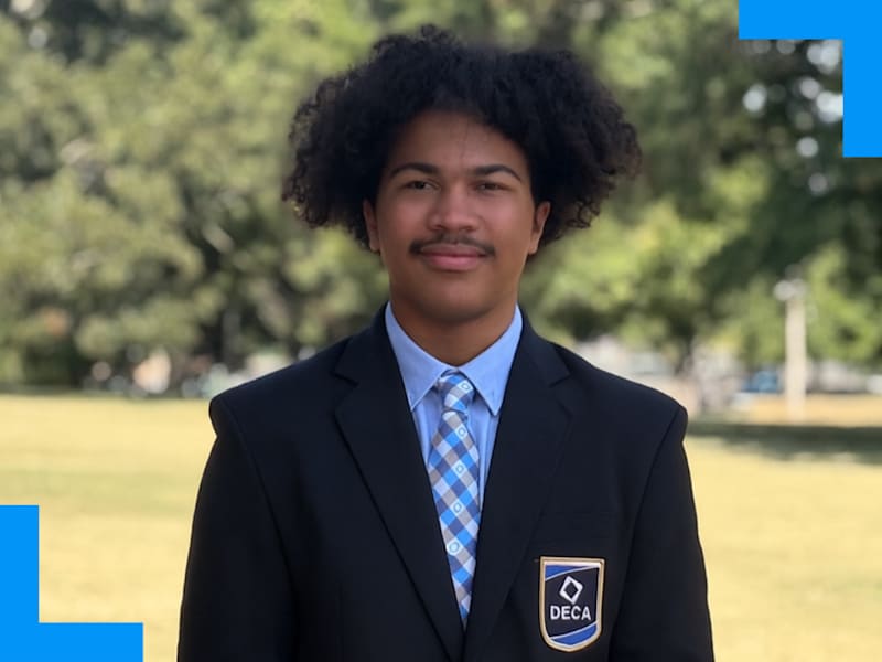 A boy in a suit with a DECA patch poses for a photo outside Parkview High School.