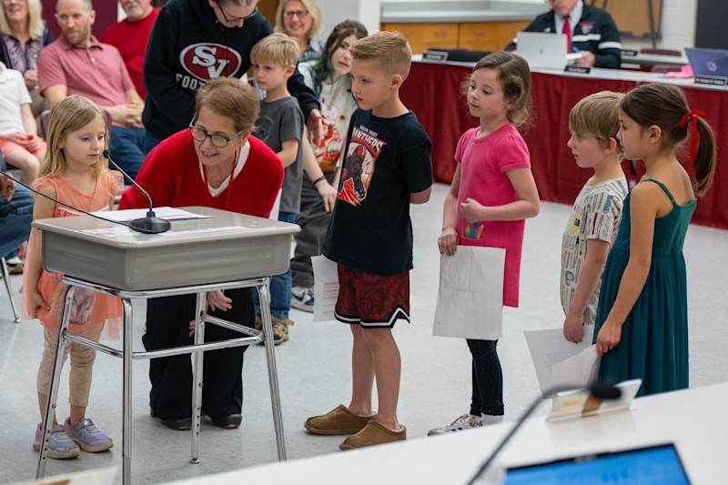 Students line up at the podium to read aloud the nominations submitted by their teachers