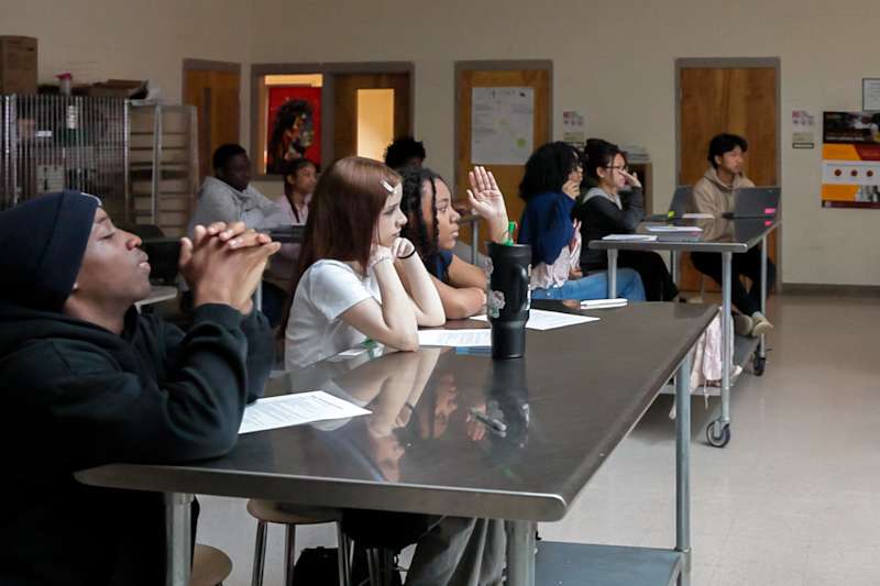 High school students actively tracking instructions and writing on a digital interactive whiteboard.