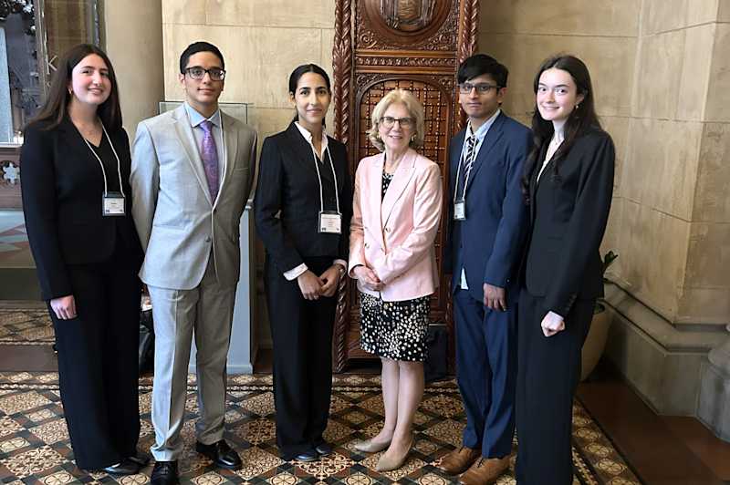 Two students stand with politicians on NYS Capitol