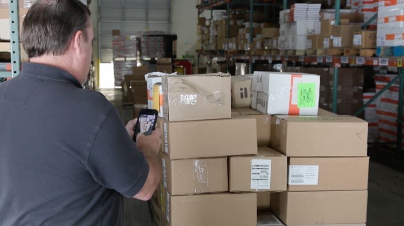 An operational technician employing a logistics scanning mobile tool inside a CMS distribution warehouse facility.
