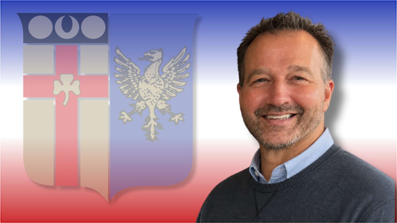 A photo of Mr. Slater on a blue and red background with the school logo