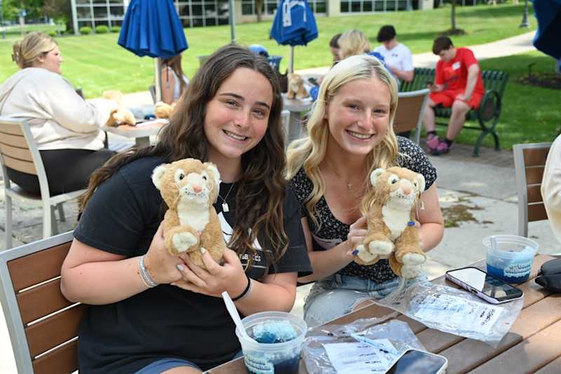 Two Misericordia University students holding Cougar plushies