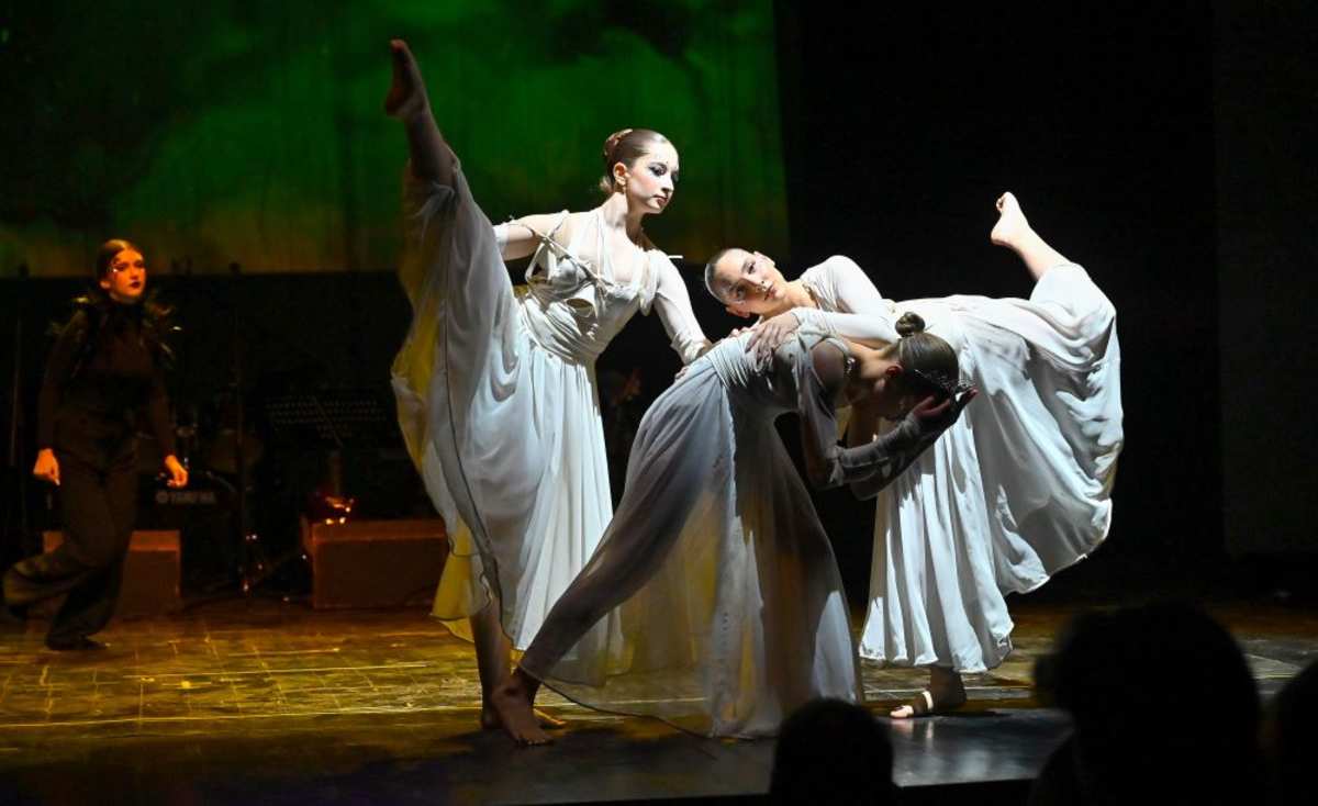 Secondary students performing a dance piece on stage at the spring performance