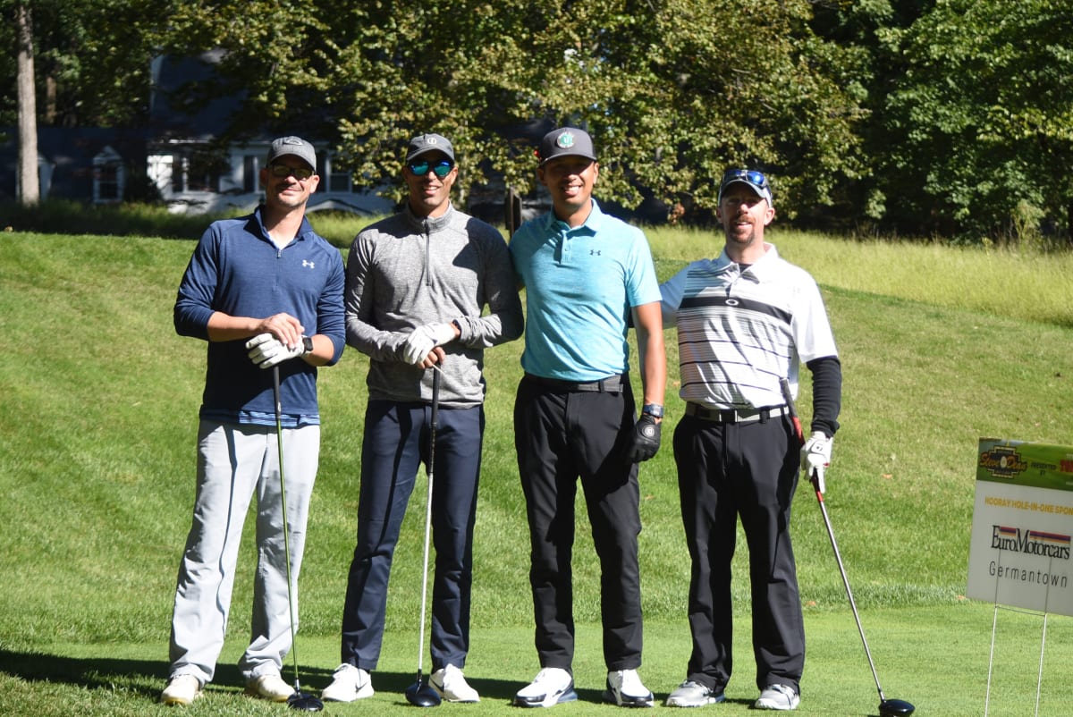 alumni posing for photo on golf course