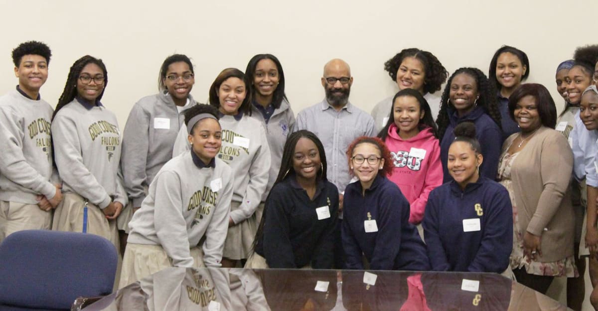 students and alumni posing in front of table