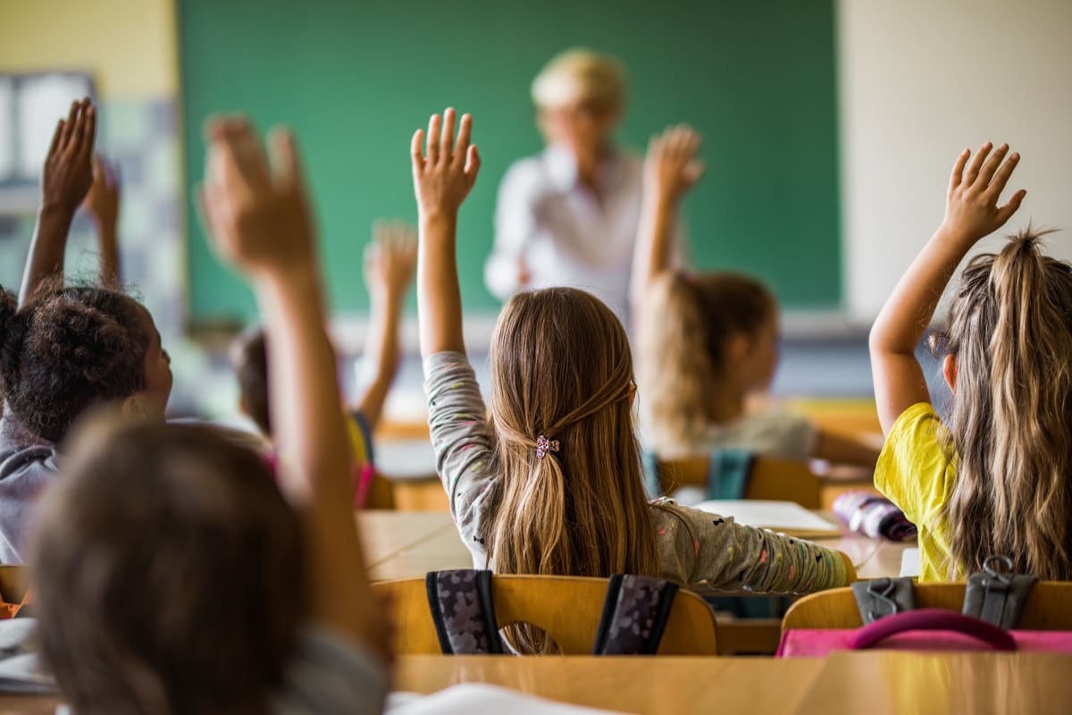 Students in Classroom Raising Hands