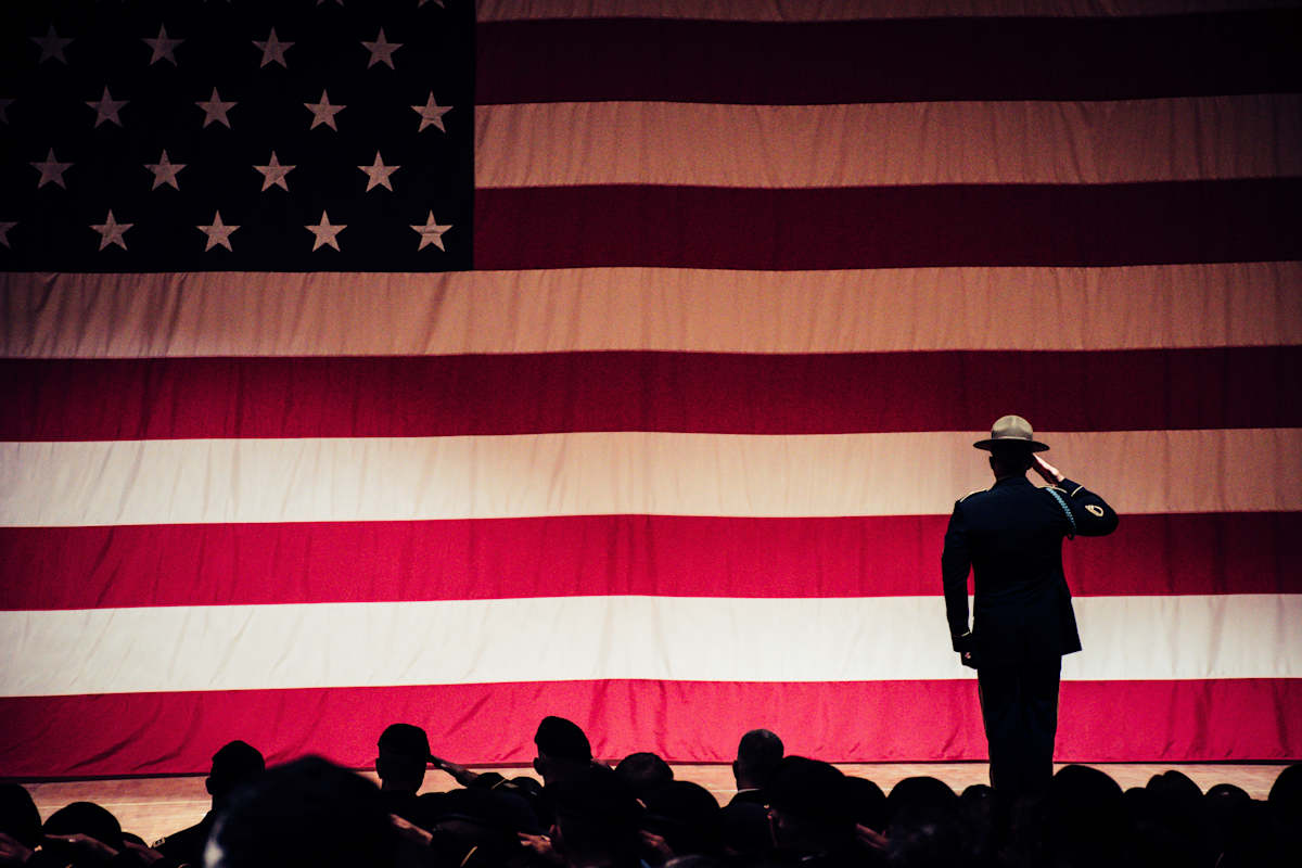 A silhouette of a man saluting an American flag