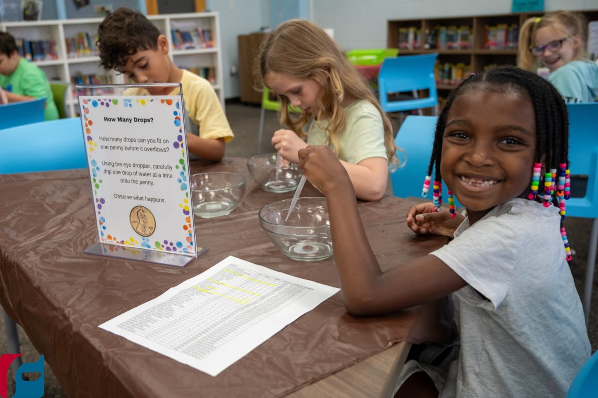 Three children performing science experiment with water drops