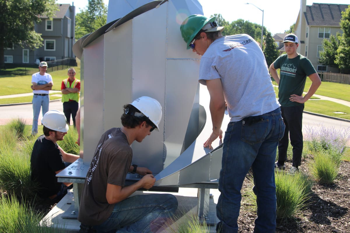 Students and teachers placing sculpture project