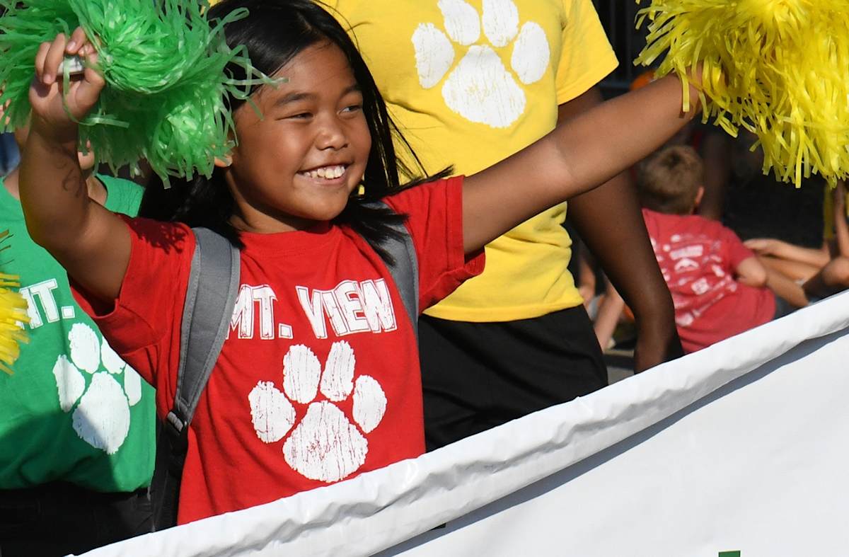 elementary student waving pom poms at parade