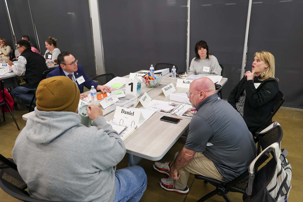 A group sits around a table discussing materials during the facilities planning meeting.