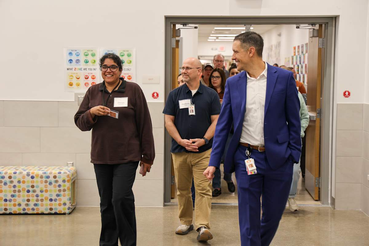 Several Long Range Facilities Planning Committee participants walk through a school hallway.