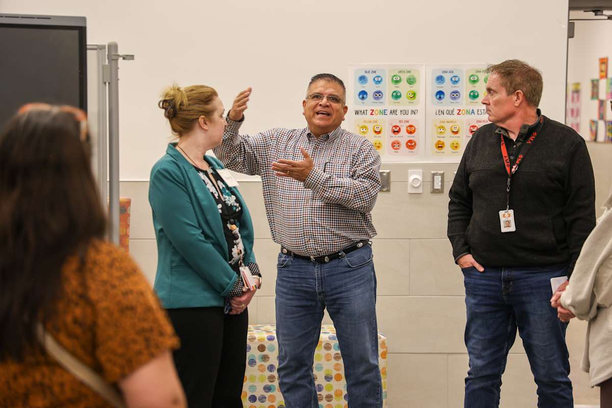A group participates in a discussion while one participant gestures to the group.