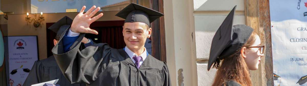 A smiling CCI graduate waves to family and friends after graduation.