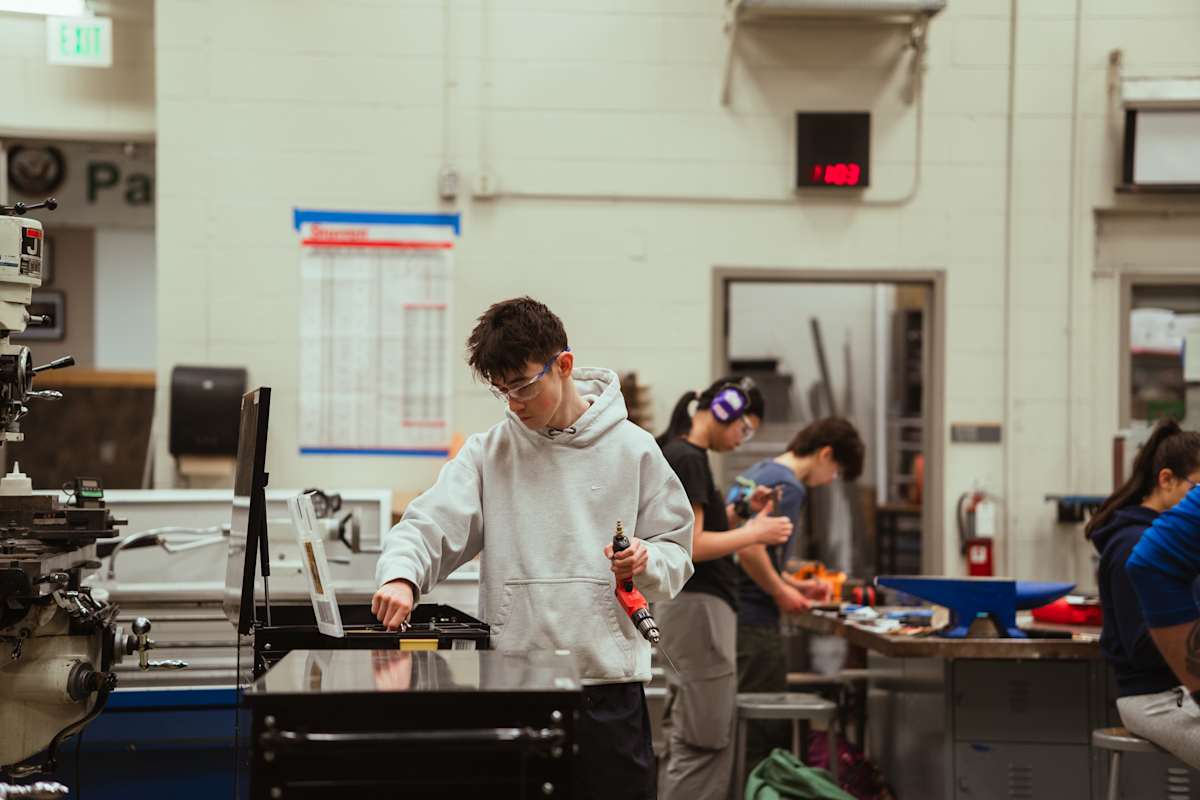Student picks up tool in workshop