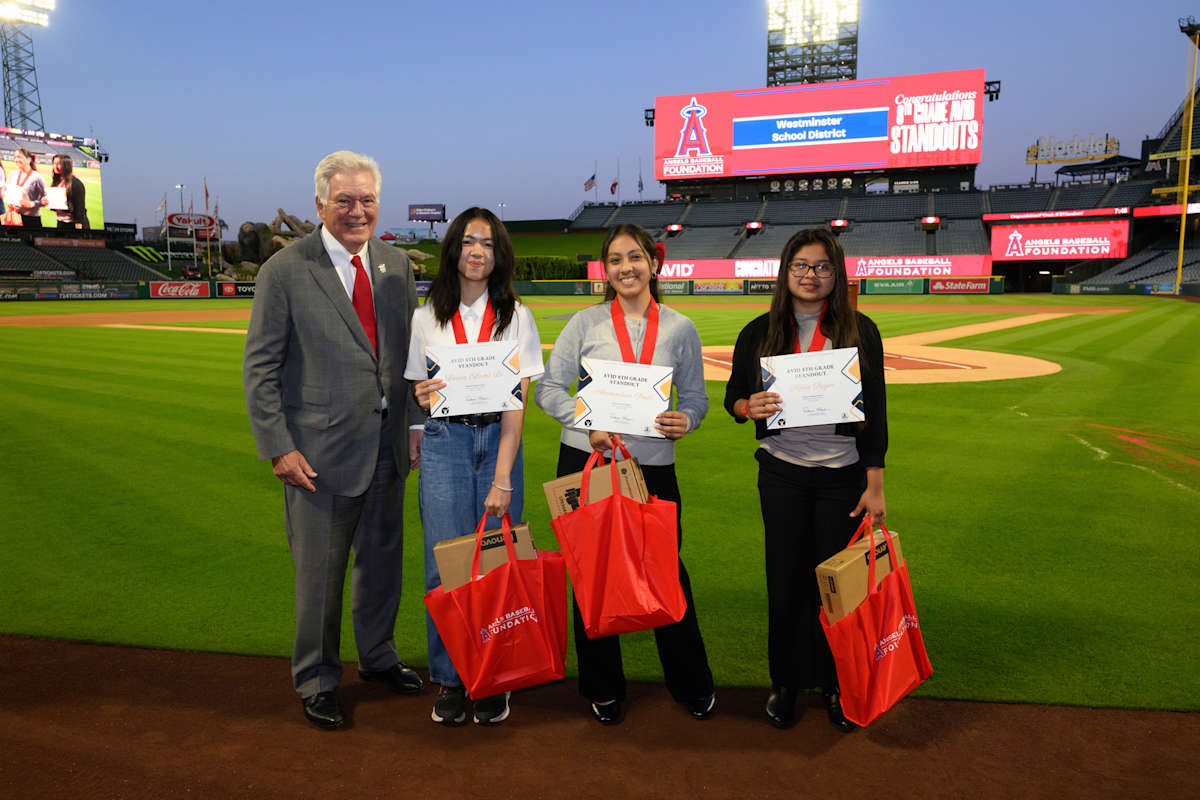 Three WSD students standing on the Angels Stadium field showing their awards.