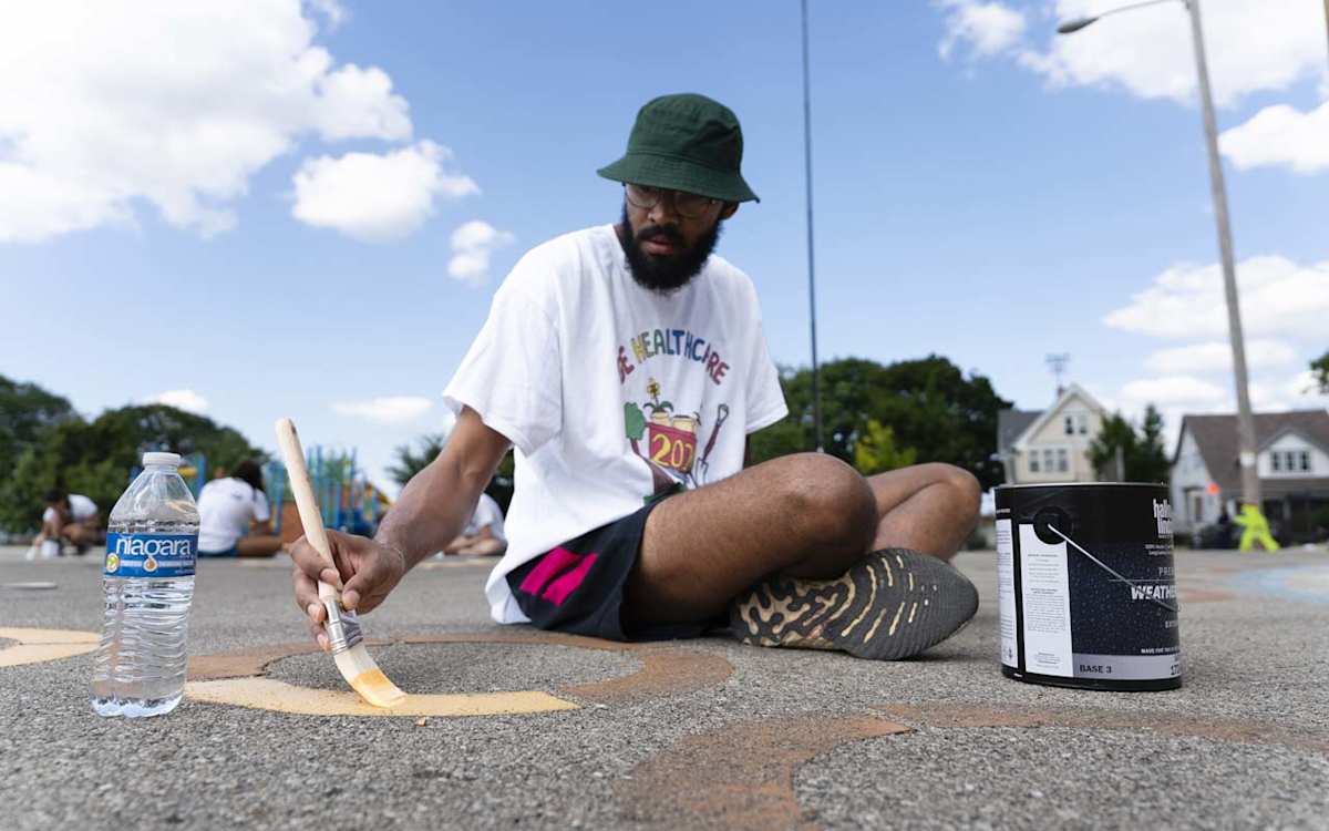 A GE HealthCare volunteer paints circles by hand on the ALBA playground.