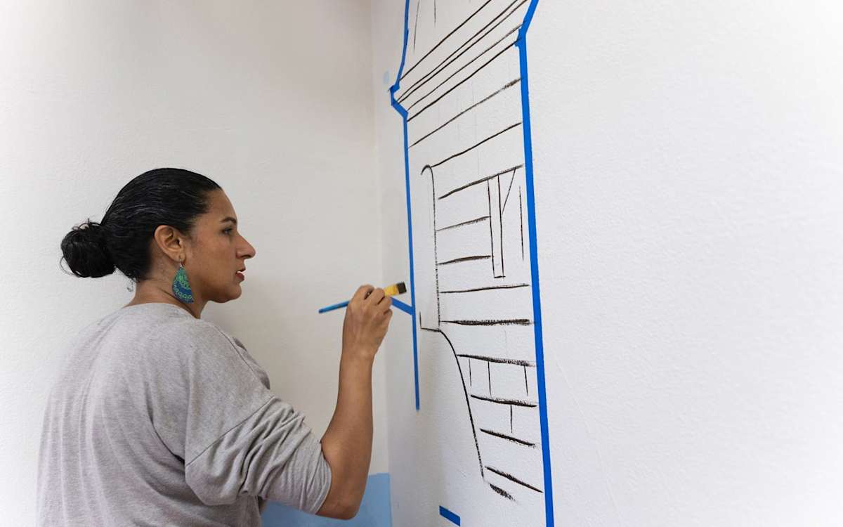 Reynaldo Hernandez's daughter, Rosalia, who also is a muralist, paints details on part of her father's mural at ALBA.