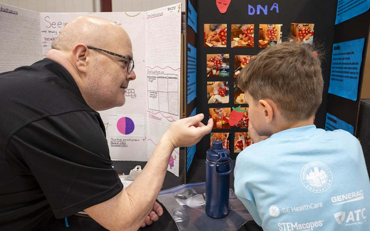 A judge discusses a student's project with him at the MPS Steam Fair.